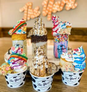 Three shakes from The Yard Milkshake Bar lined up with their corresponding sundaes in front. 