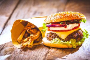 A loaded hamburger and a side of fries sitting on a wooden table. 